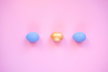 Gold and blue easter eggs on pink background.