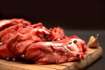 Raw marbled beef meat sprinkled with peas on a wooden cutting board with copy space