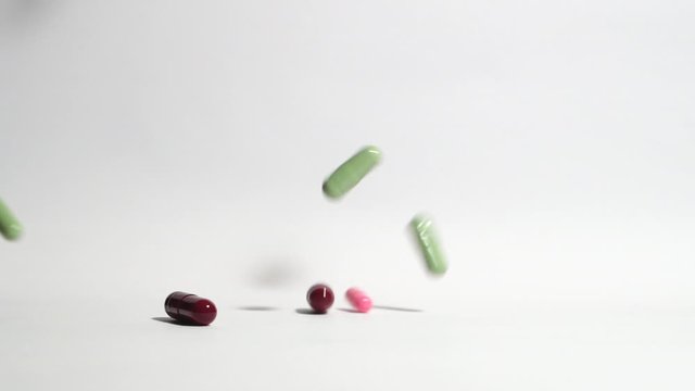 Pills and medicines falling in slow motion on white background. Cure and treatment against viruses and bacteria. Vitamin complex. Slow motion. Macro shot, detail.