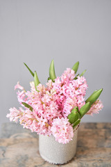 Bouquets of pink hyacinths in vase on wooden table. Spring flowers from Dutch gardener. Concept of a florist in a flower shop. Wallpaper.