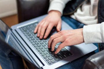 Closeup of young man using laptop at home