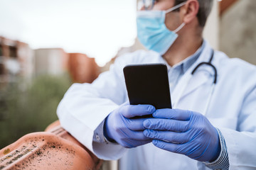 doctor man taking a break, using mobile phone. Wearing protective gloves, mask and stethoscope. coronavirus covid-19 concept