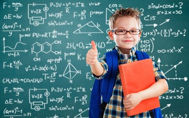 Schoolboy in glasses on blackboard background