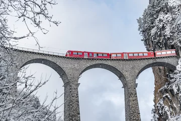Photo sur Plexiglas Viaduc de Landwasser Le viaduc de Landwasser avec le célèbre train de couleur rouge à l& 39 heure d& 39 hiver, monument de la Suisse, neige, Glacier express