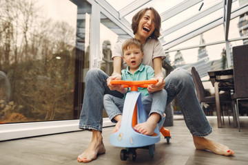 Beautiful woman with child. Woman in a gray t-shirt. Family go around the apartment on a toy car.