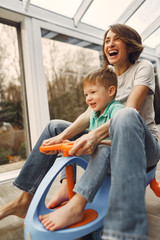 Beautiful woman with child. Woman in a gray t-shirt. Family go around the apartment on a toy car.