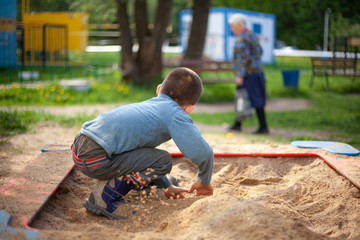 The child plays in the sandbox.