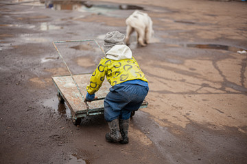 A child plays with a cart on the street.
