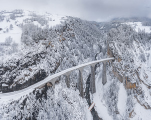 Aerial View of the Landwasser Viaduct with Railway without famous train at winter, landmark of Switzerland, snowing, river and mountains