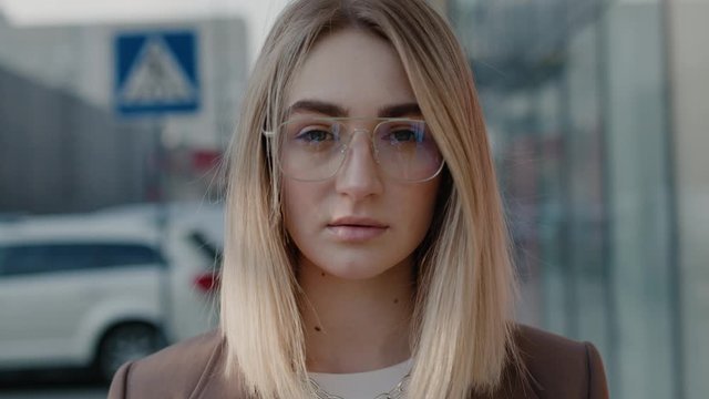 Extrime close up view of beautiful stylish blonde young woman in glasses looking to the camera sunny day successful female business spring slow motion portrait