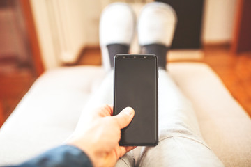 Man sitting on the couch with his cell phone.