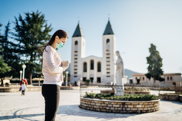 Woman wearing mask and gloves praying to God due to novel coronavirus covid-19 outbreak in Medjugorje.Woman in emotional stress and pain.Christianity.Strong religion,faith and hope concept