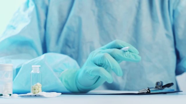 Coronavirus disease. Drug therapy. Doctor in protective equipment prescribing ampule medication.