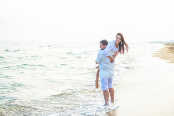 Riding on her husband. Newlywed couple in love having fun and fooling around on the sea coast