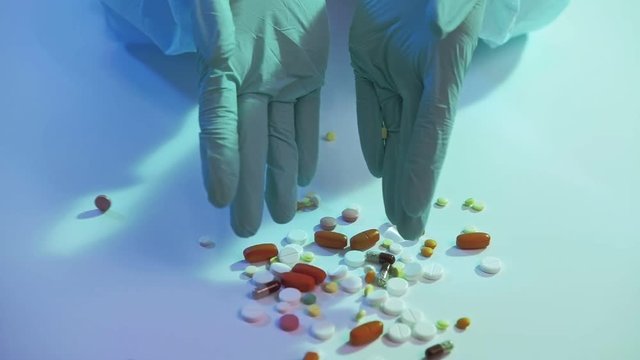 Medication dosage. Viral infection treatment. Hands in protective gloves scattering drugs.