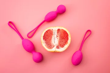 Foto auf Alu-Dibond Metaphor for pelvic floor exercises, gynecology and treat urinary incontinence through strength exercise concept with kegel weights and half a grapefruit isolated on pink background © Victor Moussa