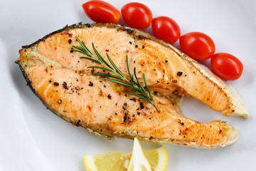 Salmon steak with herbs and spices rosemary lemon tomato on plate background - Close up cooked salmon fish fillet steak seafood