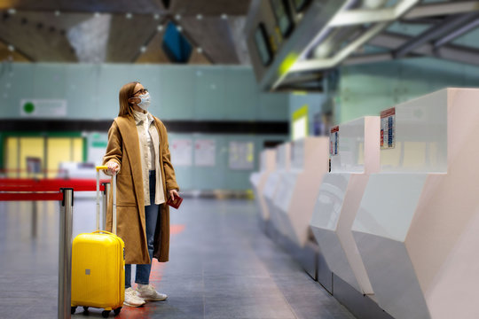 Woman with luggage stands at almost empty check-in counters at the airport terminal due to coronavirus pandemic/Covid-19 outbreak travel restrictions. Flight cancellation.Quarantine all over the world