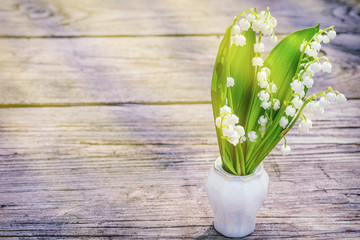 Flower Spring Sun White Green Background Horizontal. Lilies of the valley standing spring flowers bouquet in vase wooden old table in the sun. Sun rays fall beautiful spring blooming flower.