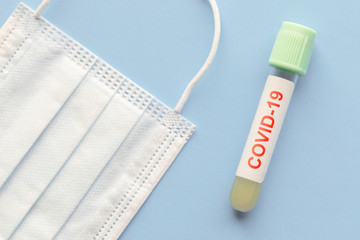 test tube with sample of coronavirus covid-19 and medical mask, deadly global pandemic concept