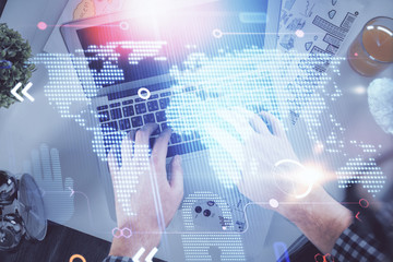 Multi exposure of man's hands typing over computer keyboard and world map hologram drawing. Top view. Technology concept.
