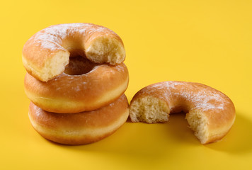 donuts with some bites on a yellow background