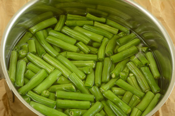 Fresh raw cut green beans in water inside stainless steel cooking pot