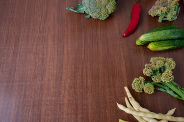 Harvest vegetables on the table: broccoli, red pepper, cucumbers, beans. Empty space for text