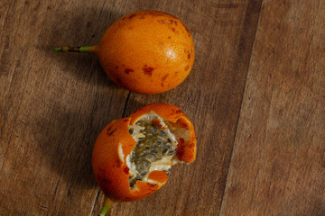One closed and one open granadilla on a wooden background