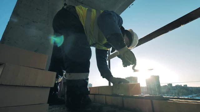 Construction worker is laying bricks and cement