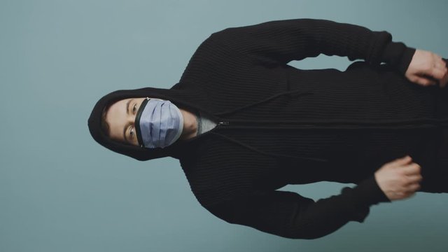 Portrait of young man in protective mask and hoodie, zipping up jacket, looking confidently in future, not panic, believe that personal responsibility will put end to the coronavirus pandemic.