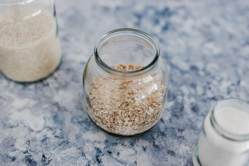 non-perishable food ingredients for vegan pantry, glass jars with oats flour and rice