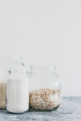 non-perishable food ingredients for vegan pantry, glass jars with oats flour and rice