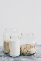 non-perishable food ingredients for vegan pantry, glass jars with oats flour and rice