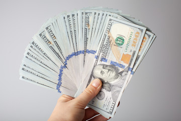 Many hundred dollar bills in a semicircle in hand