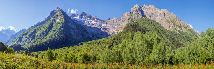Fototapeta na wymiar Panorama Caucasus Mountains, Dombay. Glacier, sharp peaks and forest. 