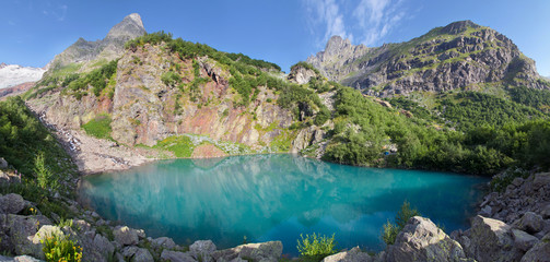 A picturesque lake in the Caucasus Mountains, Dombay. Water, rocks and summer greens.