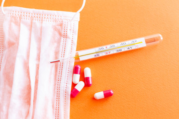glass mercury thermometer shows high temperature pills capsules red white, background color lush...