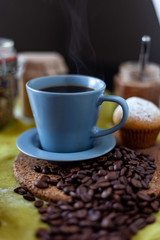 cup of coffee on a table with muffins and coffee beans
