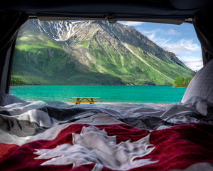 Beautiful summer time views in northern Canada with Canadian maple leaf, flag turquoise, emerald green lake and snow capped mountains in background. 