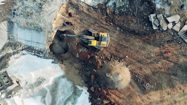Construction equipment, heavy industry machinery. One machine digs earth at a big quarry.