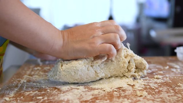 Female hands kneading dough in flour on table