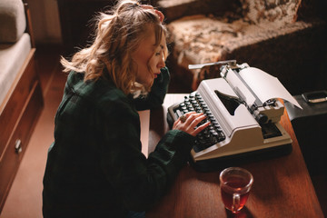 Young female writer using typewriter at home