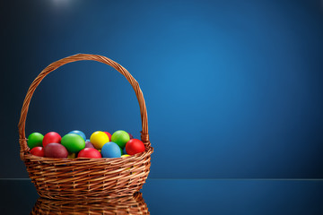 Easter color eggs in festive gift basket, blue background