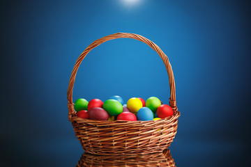 Easter color eggs in festive gift basket, blue background