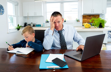 COVID-19 school lockdowns and remote working. Stressed man trying to work from home with bored son