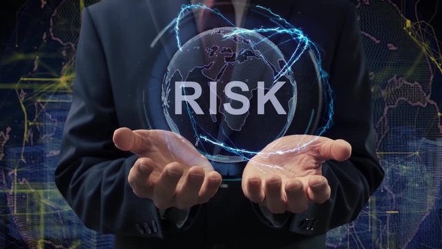 Male hands activate a conceptual holographic text Risk. Businessman in a suit with a hologram of planet Earth on a background of a futuristic wireframe city