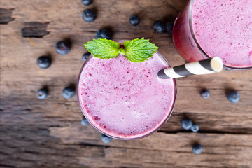 Blueberry smoothie purple colorful fruit juice milkshake blend beverage healthy high protein the taste yummy In glass drink episode morning on a wooden background from top view.