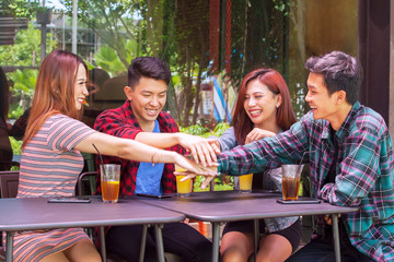 Friends joining hands to success together in cafe