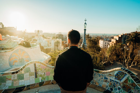 Young male tourist spending vacation in Barcelona,Spain.Traveling to Europe,visiting Parc Guell UNESCO site famous historical landmarks.Tourist at terrace of Guell, Gaudi's park.